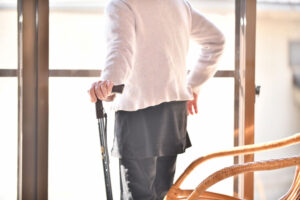 杖をついて窓の外を見る女性