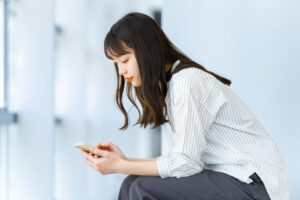 前かがみにスマホを操作する女性