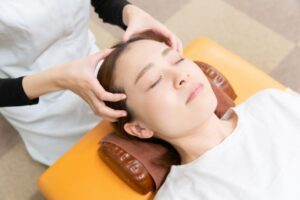 整体院で頭のツボ押し施術を受けている女性