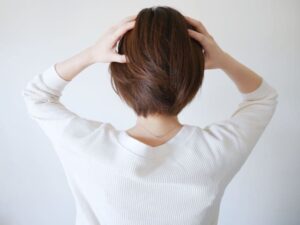 両手で頭をおさえる女性